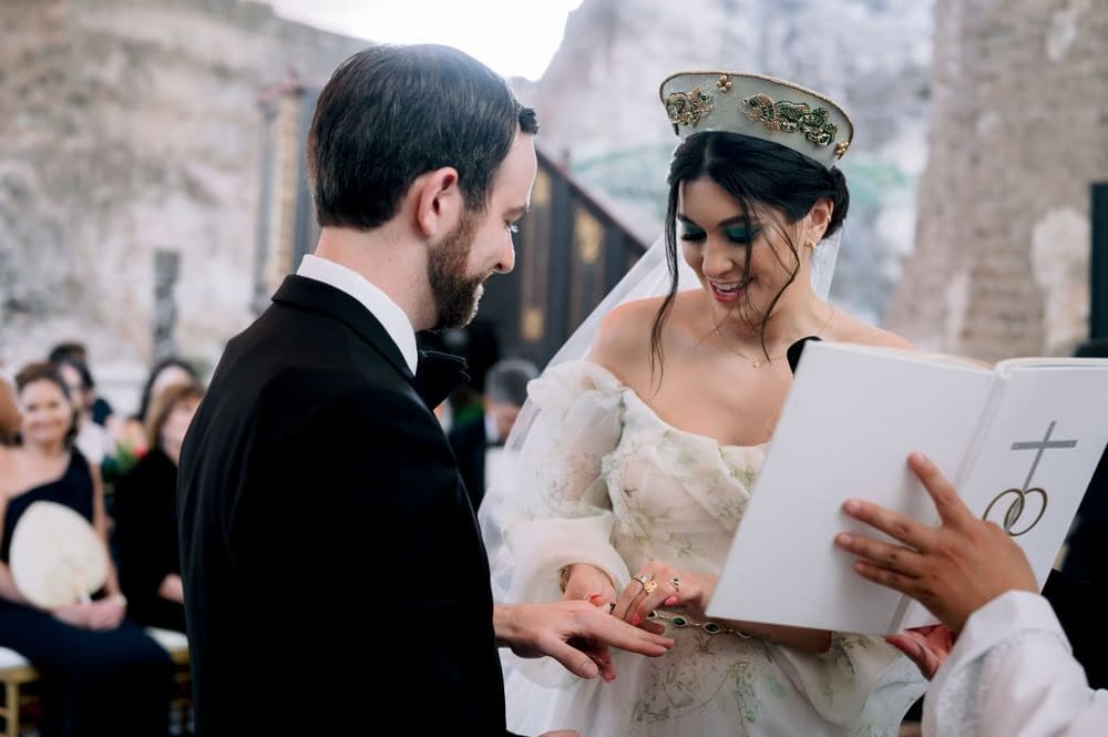 Bride smiles as the groom slides on her wedding ring during the outdoor ceremony at Casa Santo Domingo.