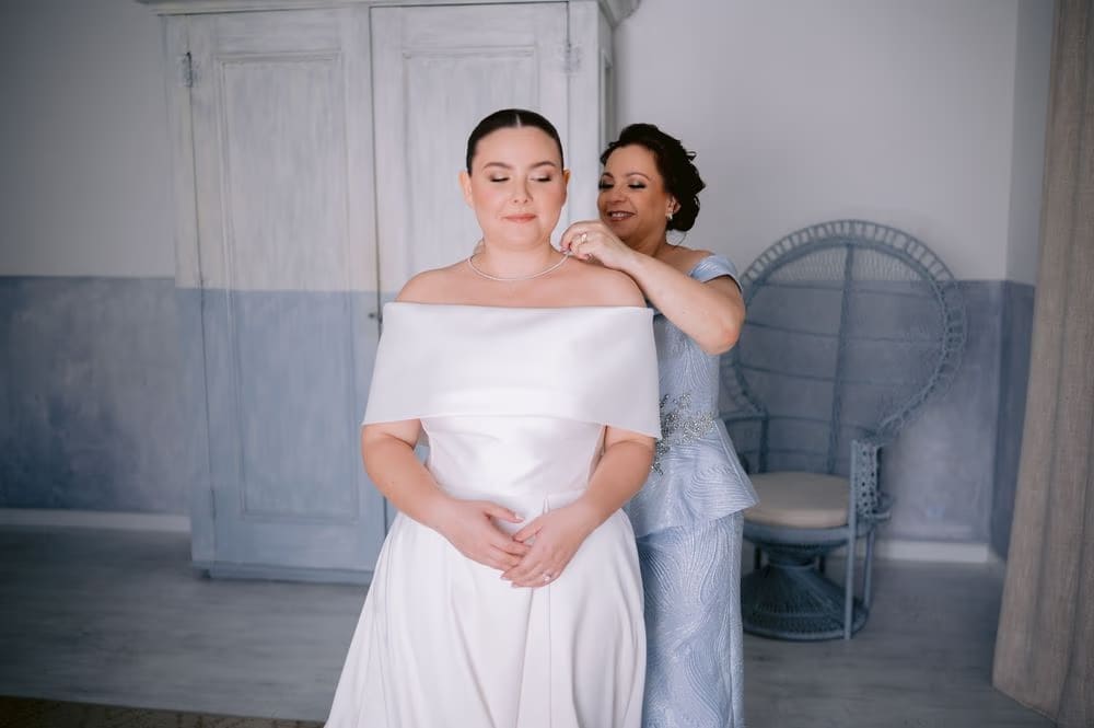 The bride's mother fastens her necklace as she finishes getting ready — Jessie Harrison makeup, Antigua Guatemala wedding.