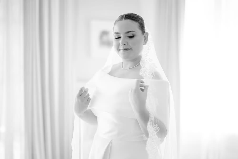 Black-and-white portrait of the bride with her lace-edged cathedral veil — editorial bridal look.