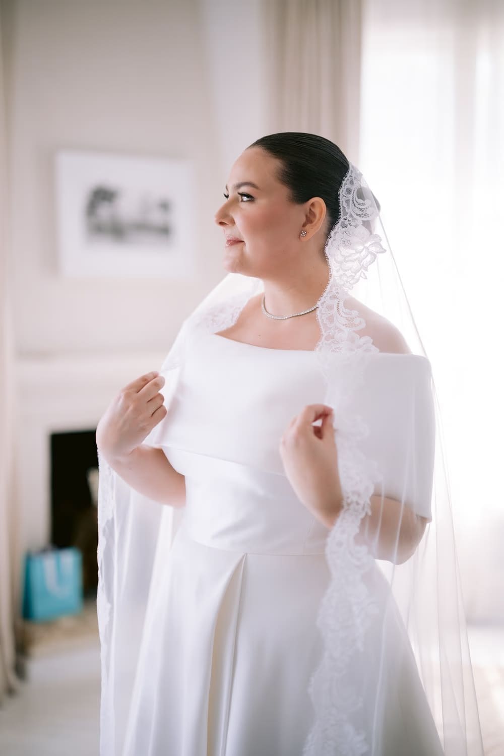 Johanna poses in her lace mantilla veil and modern off-shoulder gown — Jessie Harrison makeup.