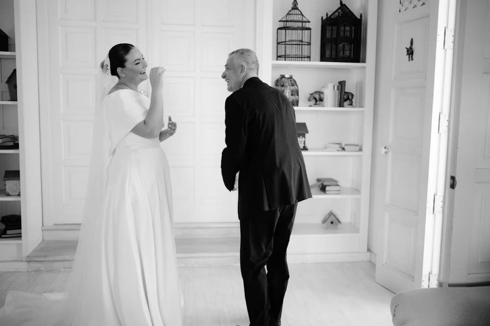 Black-and-white candid of the bride laughing with her father after the first look.