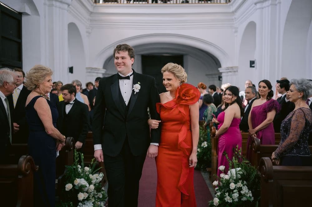 Groom Thomas walks down the aisle on his mother's arm before the ceremony in Antigua Guatemala.
