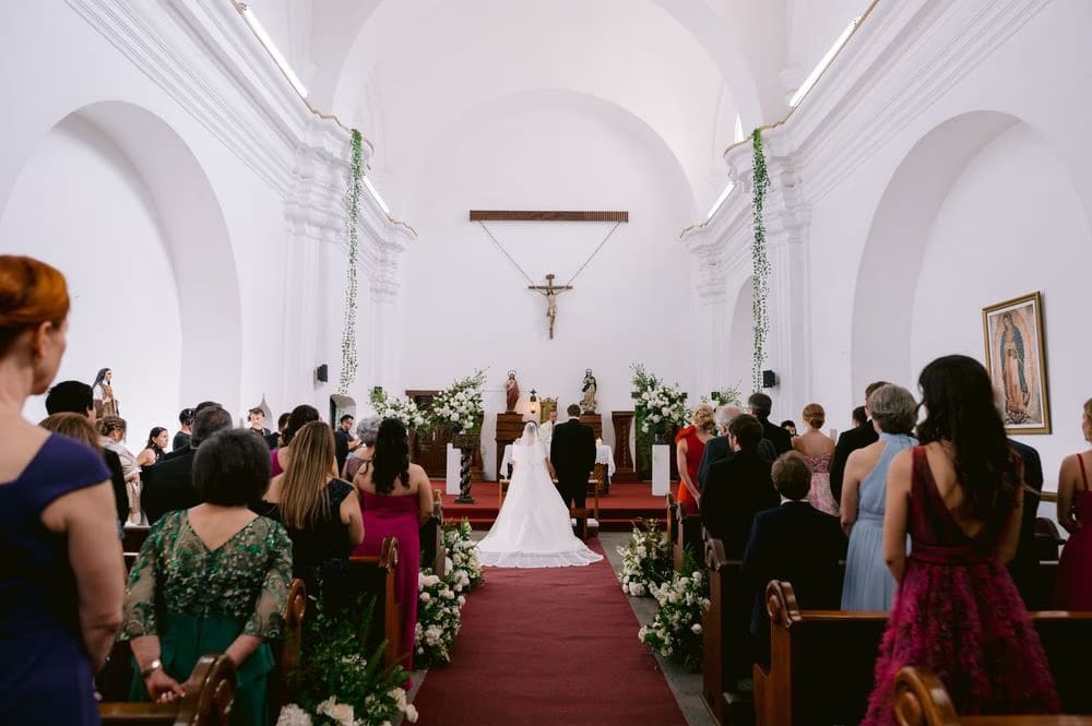 Wide view of the ceremony with the bride at the altar framed by white floral arrangements.