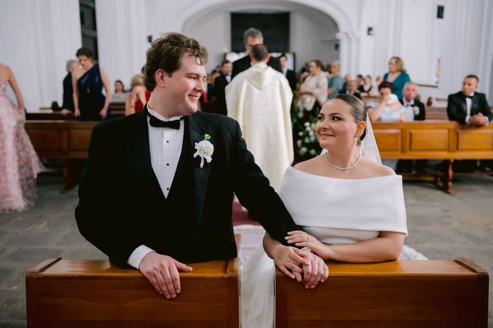 The couple shares a knowing glance from the pew during the ceremony — candid wedding moment in Antigua Guatemala.