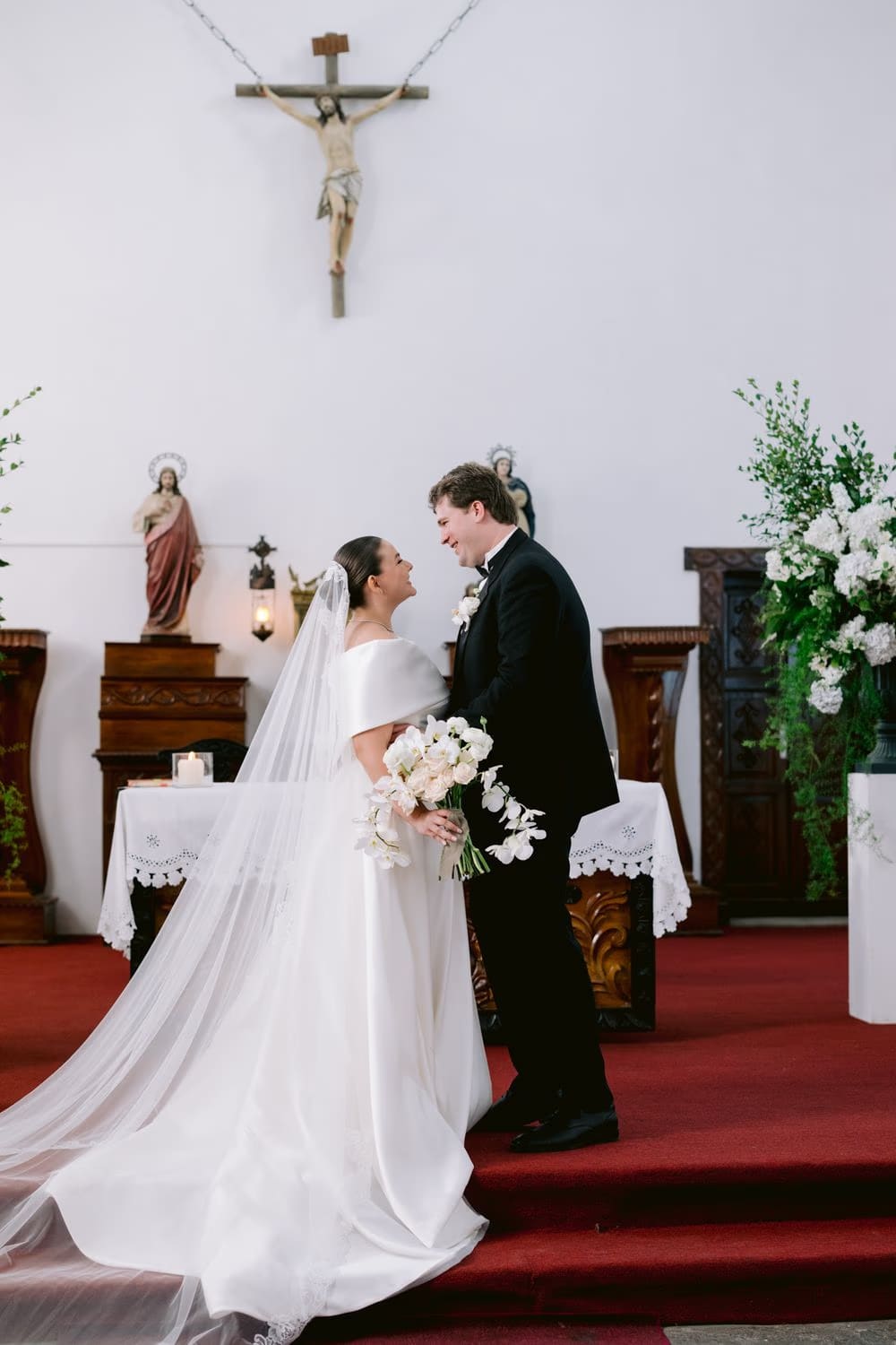 Bride and groom stand at the altar beneath the crucifix during their vows — Antigua Guatemala wedding ceremony.