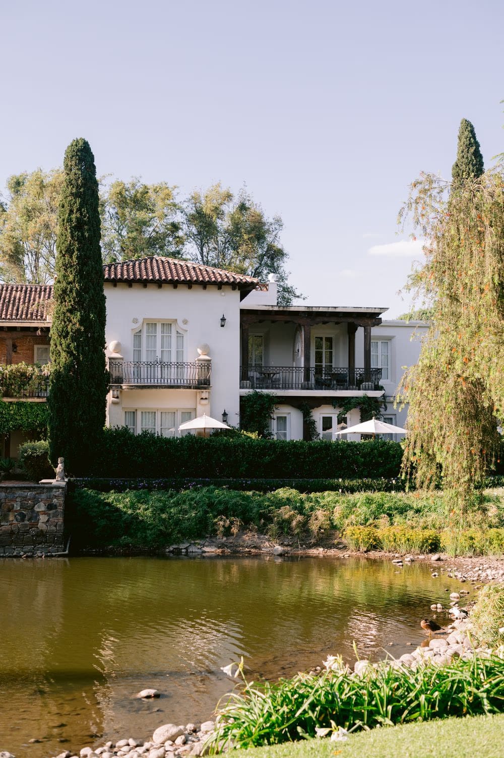 Spanish-tile colonial architecture reflects on the pond at the wedding venue in Antigua Guatemala.