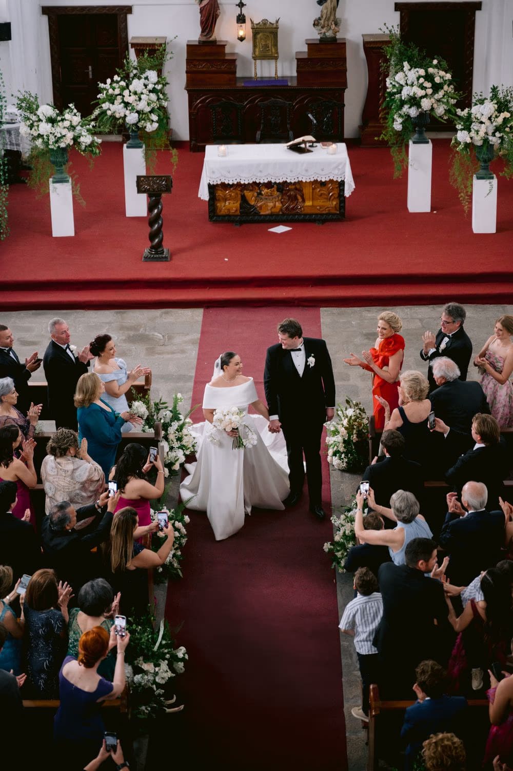 Aerial view of the bride and groom turning back at the altar as guests applaud.
