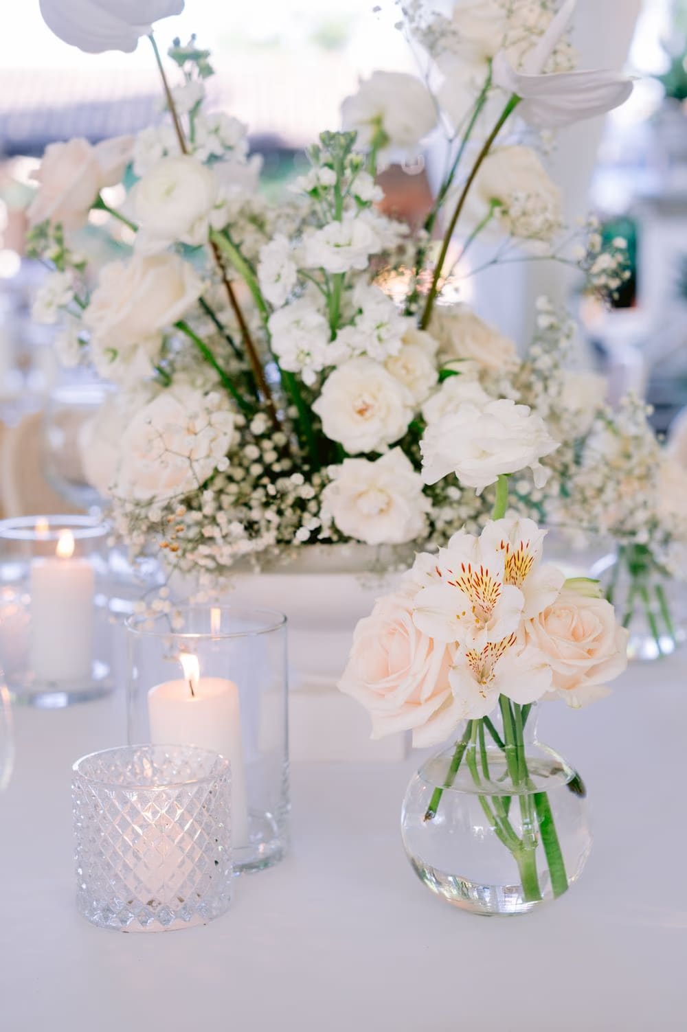 Close-up of a tablescape detail with blush roses and white florals beside crystal candle holders — Decor Guatemala.