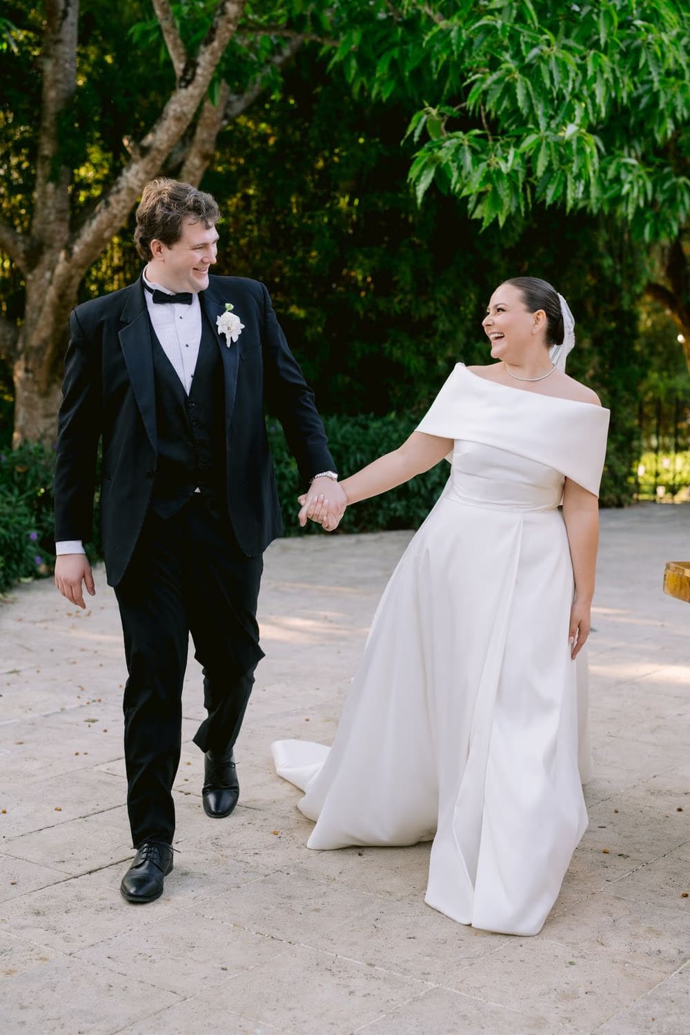 The bride laughs with the groom during their post-ceremony portrait stroll in the gardens at Villa Bokeh.