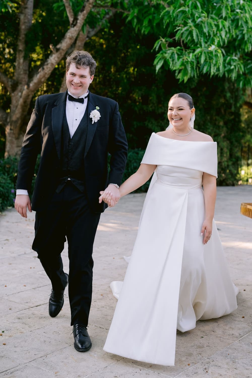 Candid portrait of the newlyweds laughing as they walk through the gardens at Villa Bokeh.