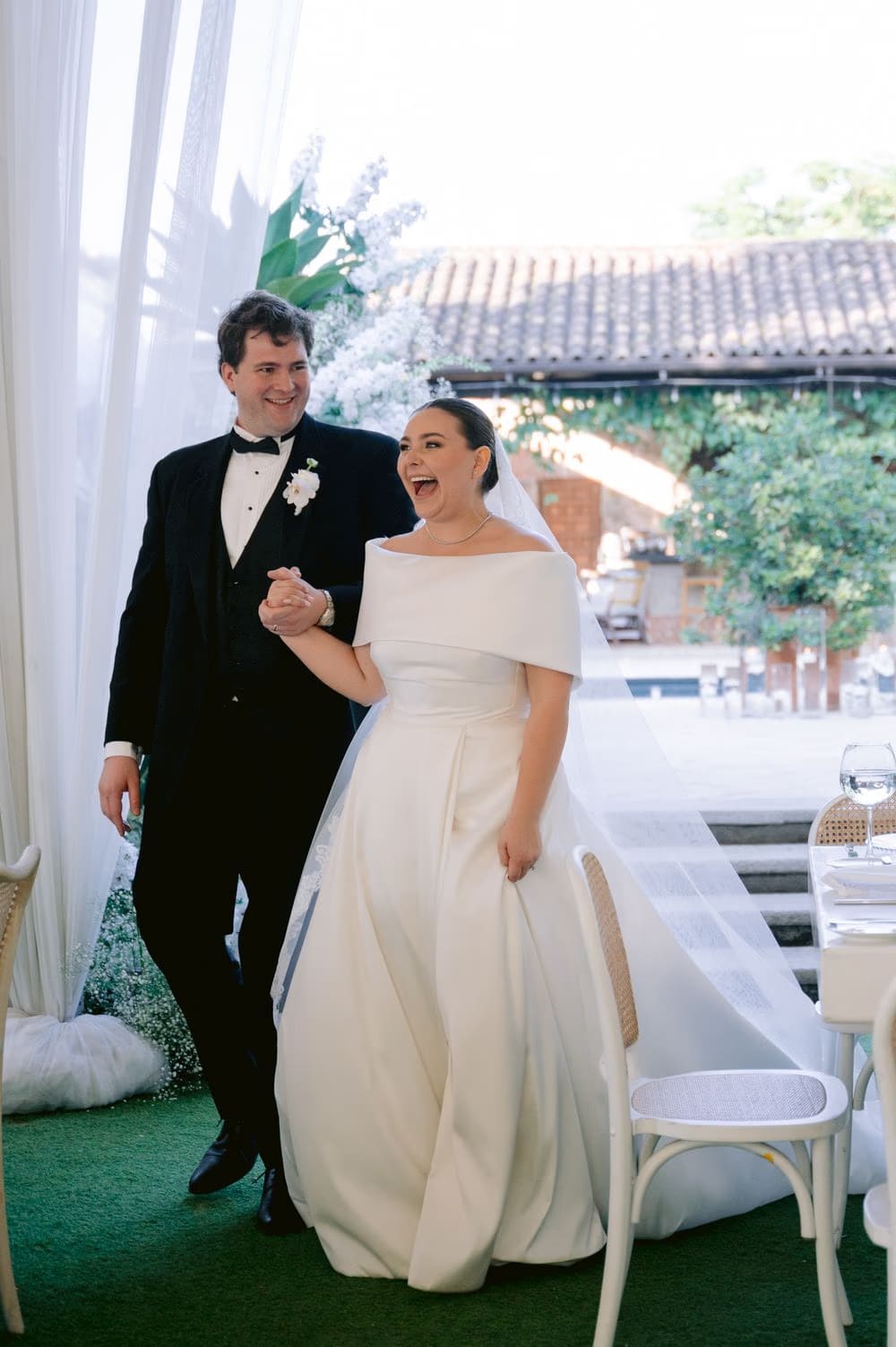 Bride and groom step into the reception tent to applause — open-air celebration at Villa Bokeh.