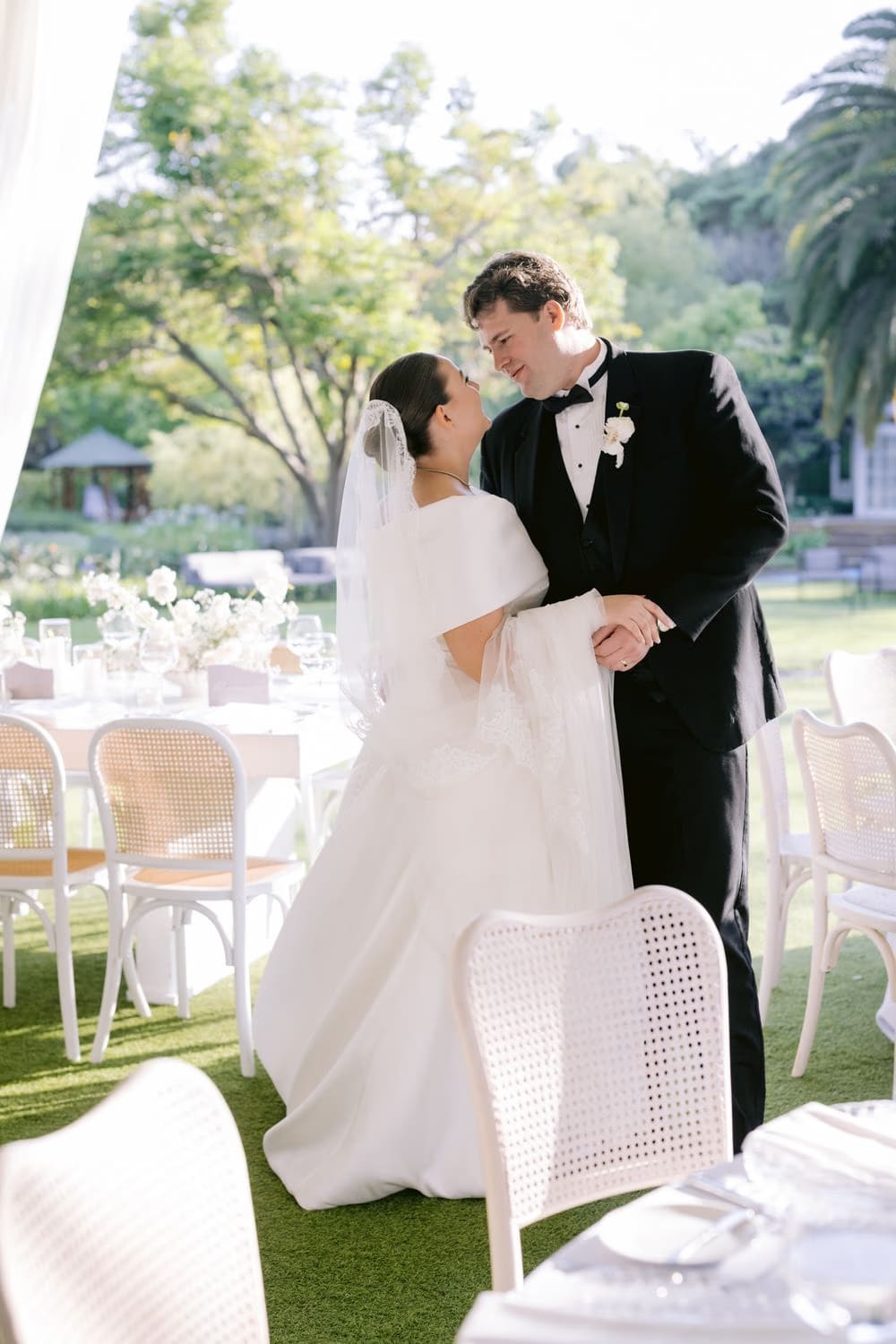 Bride and groom share a tender pause at their reception table beneath the open canopy.