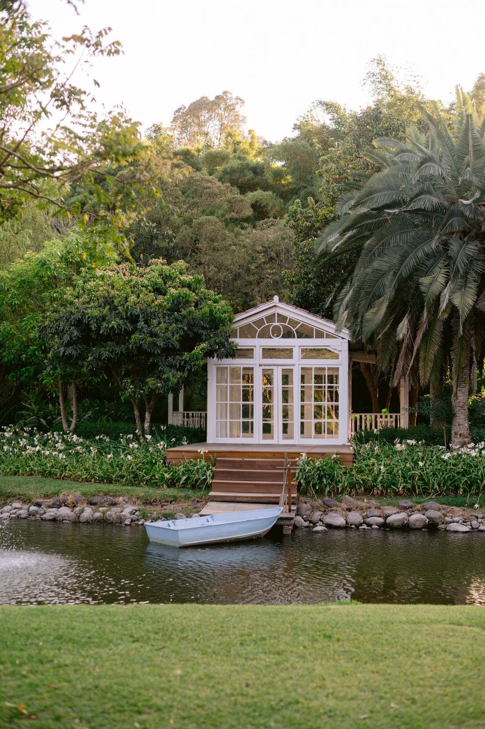 White Victorian-style glass gazebo by the lily pond at Villa Bokeh — open-air ceremony pavilion.