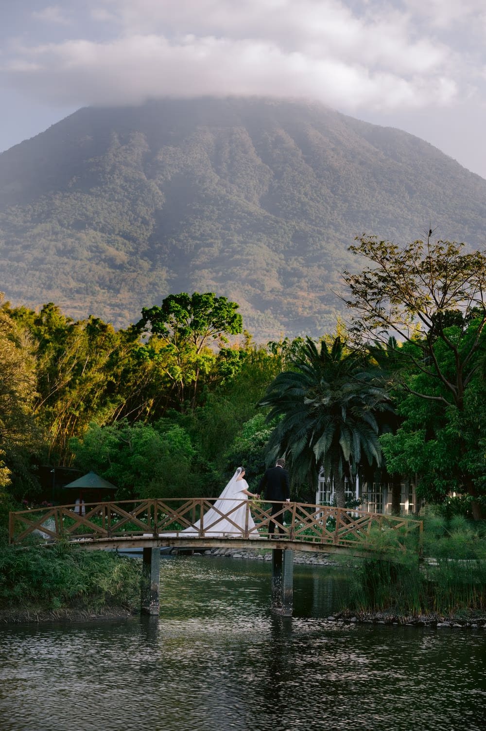 Sweeping landscape of the volcano, pond and wooden bridge at the wedding venue — destination wedding in Antigua Guatemala.