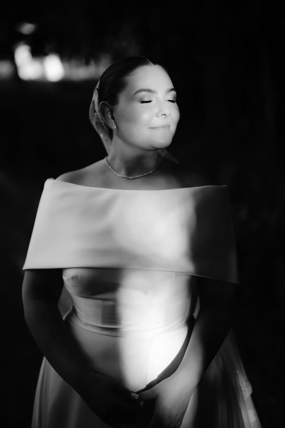 Black-and-white night portrait of the bride with a sweep of light across her gown — modern wedding portrait.