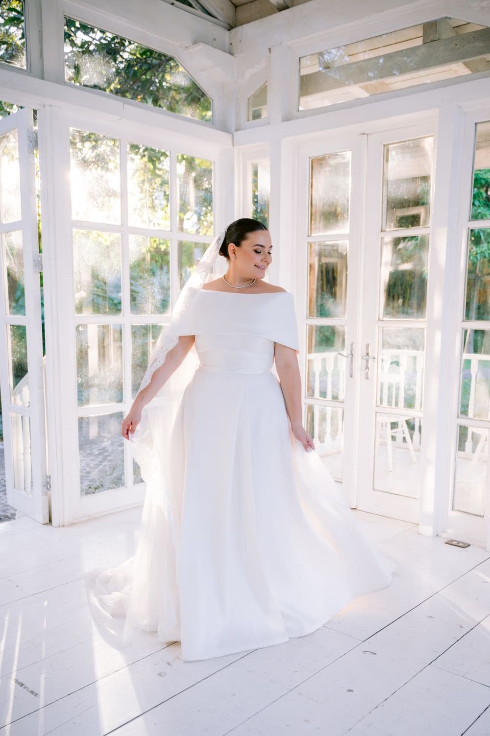 Bride twirls her gown inside the white-paneled gazebo at Villa Bokeh — modern bridal portrait.