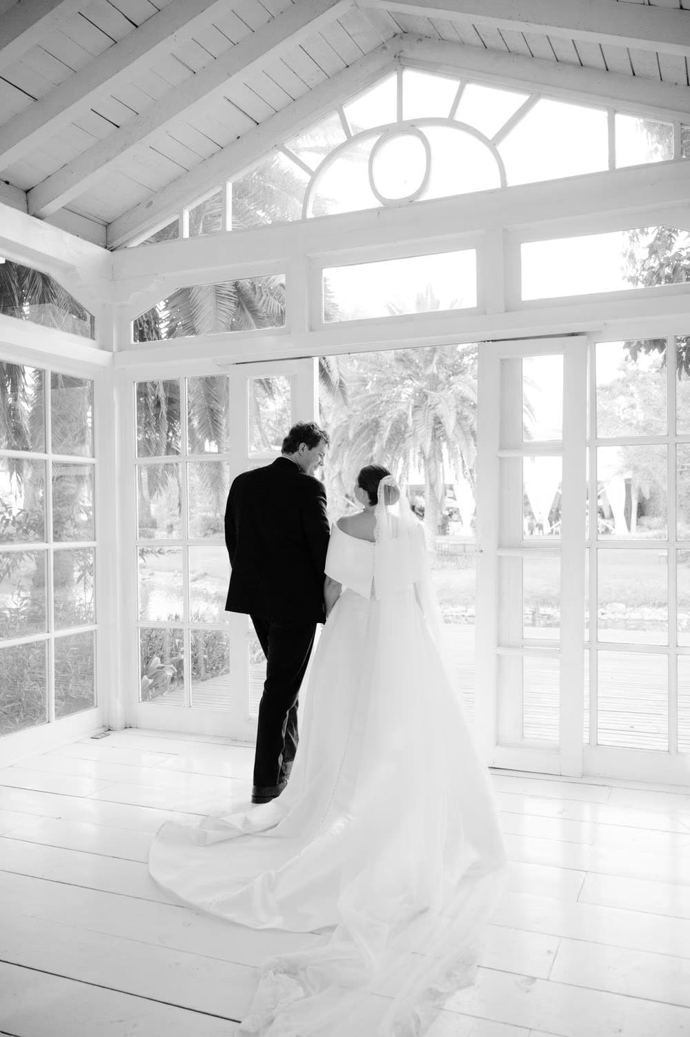 Black-and-white moment of the couple stepping out of the gazebo together — quiet wedding portrait.