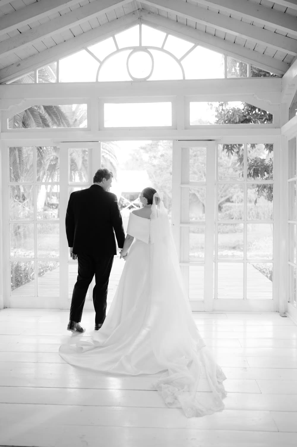 Couple silhouetted against the open doors of the glass gazebo — black-and-white portrait at Villa Bokeh.