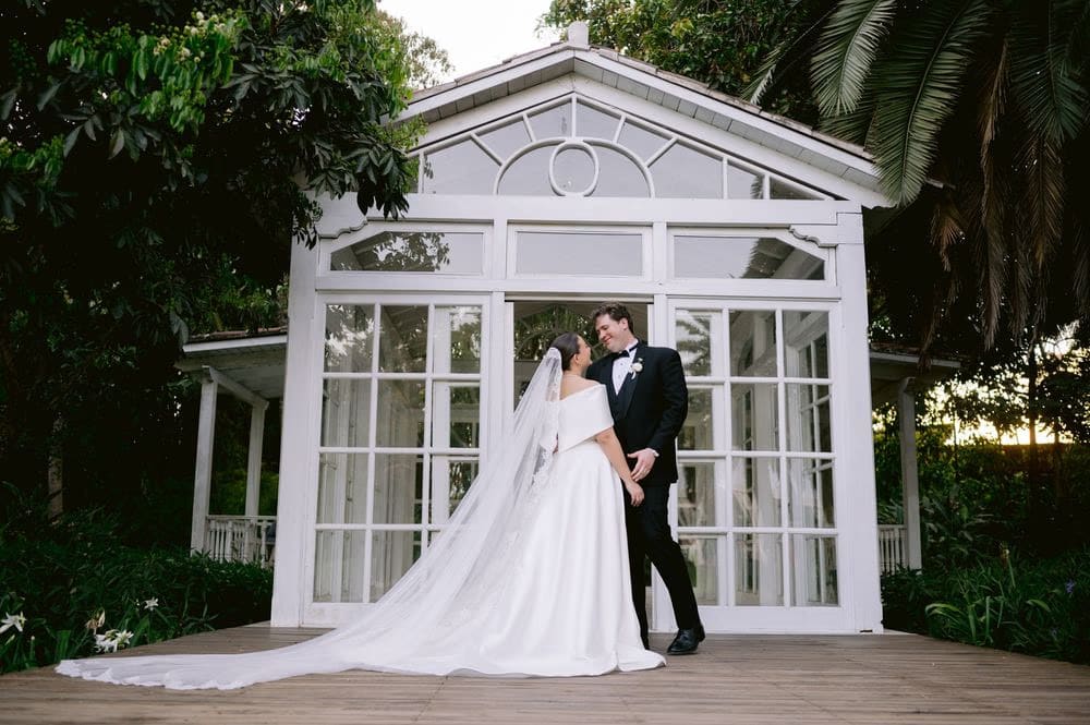 Newlyweds pose on the deck outside the white gazebo framed by tropical foliage at Villa Bokeh.