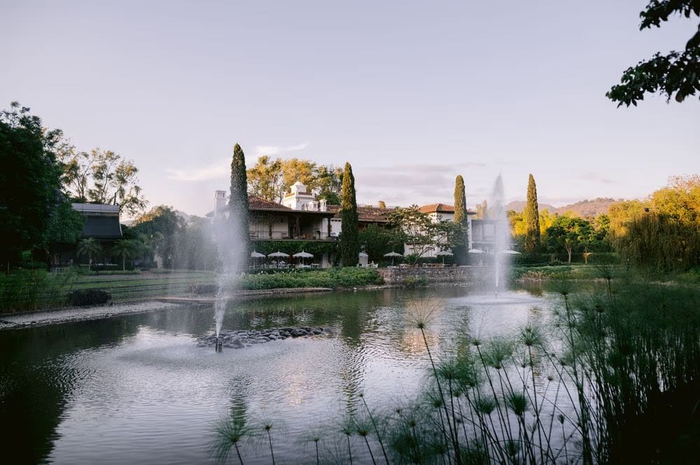 Twin fountains and the hacienda silhouette at twilight on the grounds of Villa Bokeh.