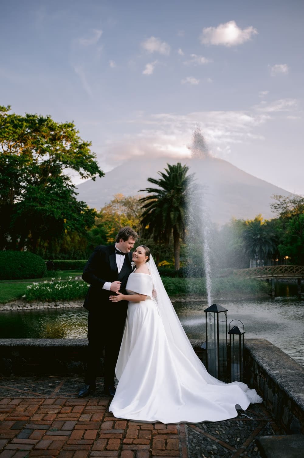 Johanna and Thomas pose on a terrace with the lit fountain and volcano backdrop at Villa Bokeh, Antigua Guatemala.