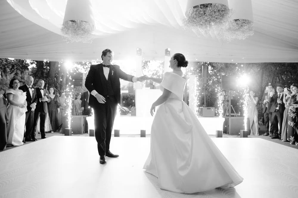 Black-and-white first-dance moment with cold sparkler fountains lighting the dance floor at Villa Bokeh.
