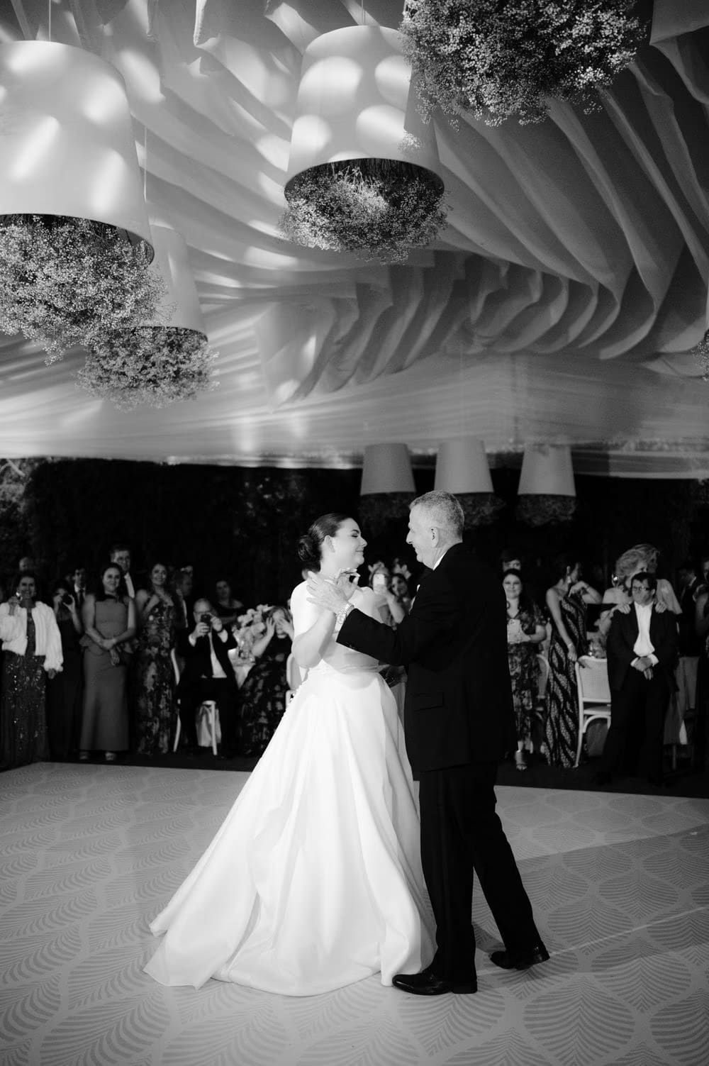 Black-and-white father-daughter dance beneath baby's breath chandeliers at the reception.