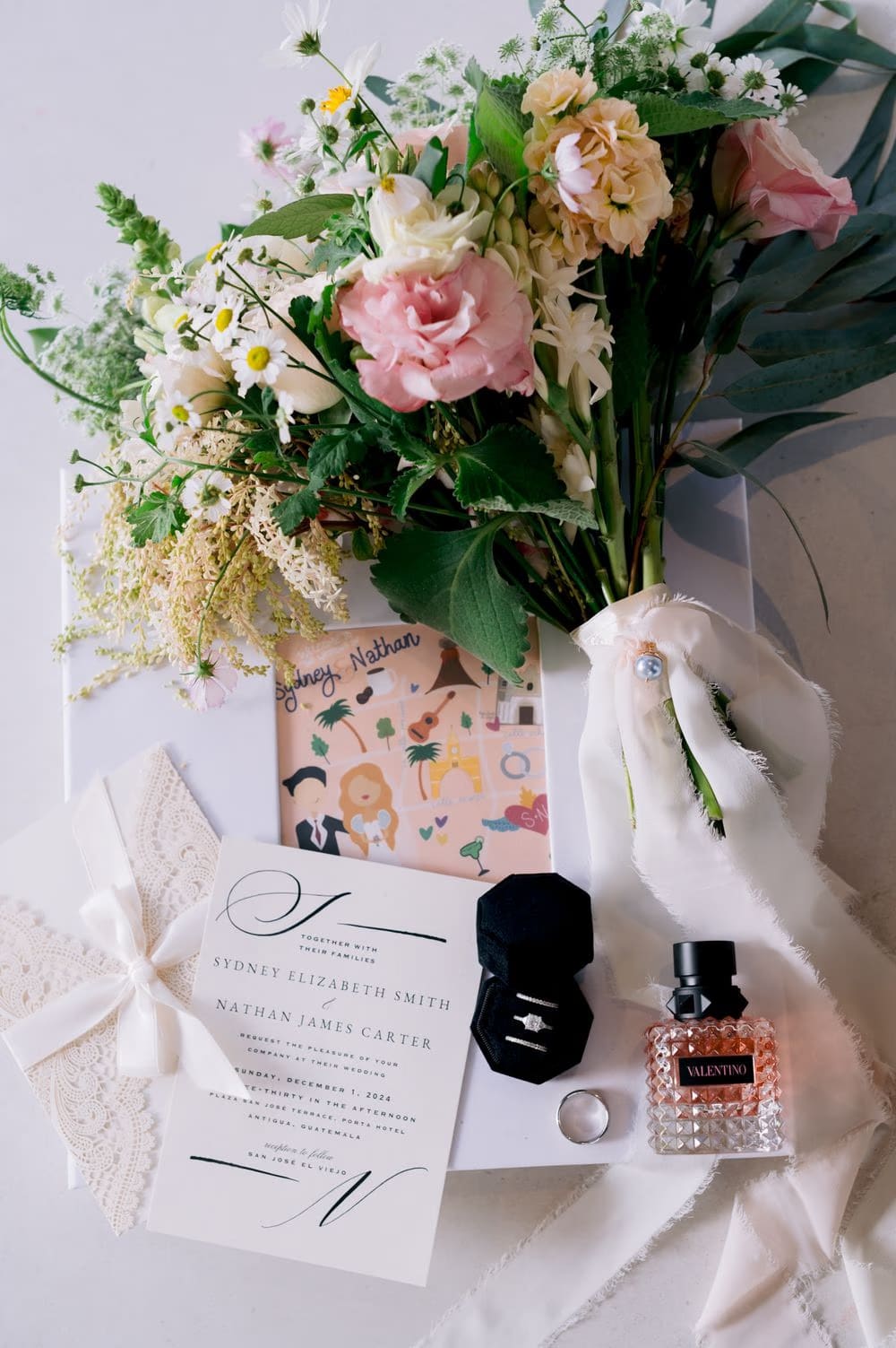 Wedding invitation, ring box, perfume and wildflower bouquet flatlay — bridal details for Sydney and Nathan's Antigua Guatemala wedding.
