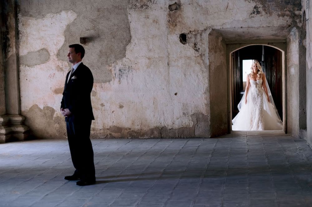 Groom waits as bride Sydney appears in the doorway during their first look at Santa Clara Ruins, Antigua Guatemala.