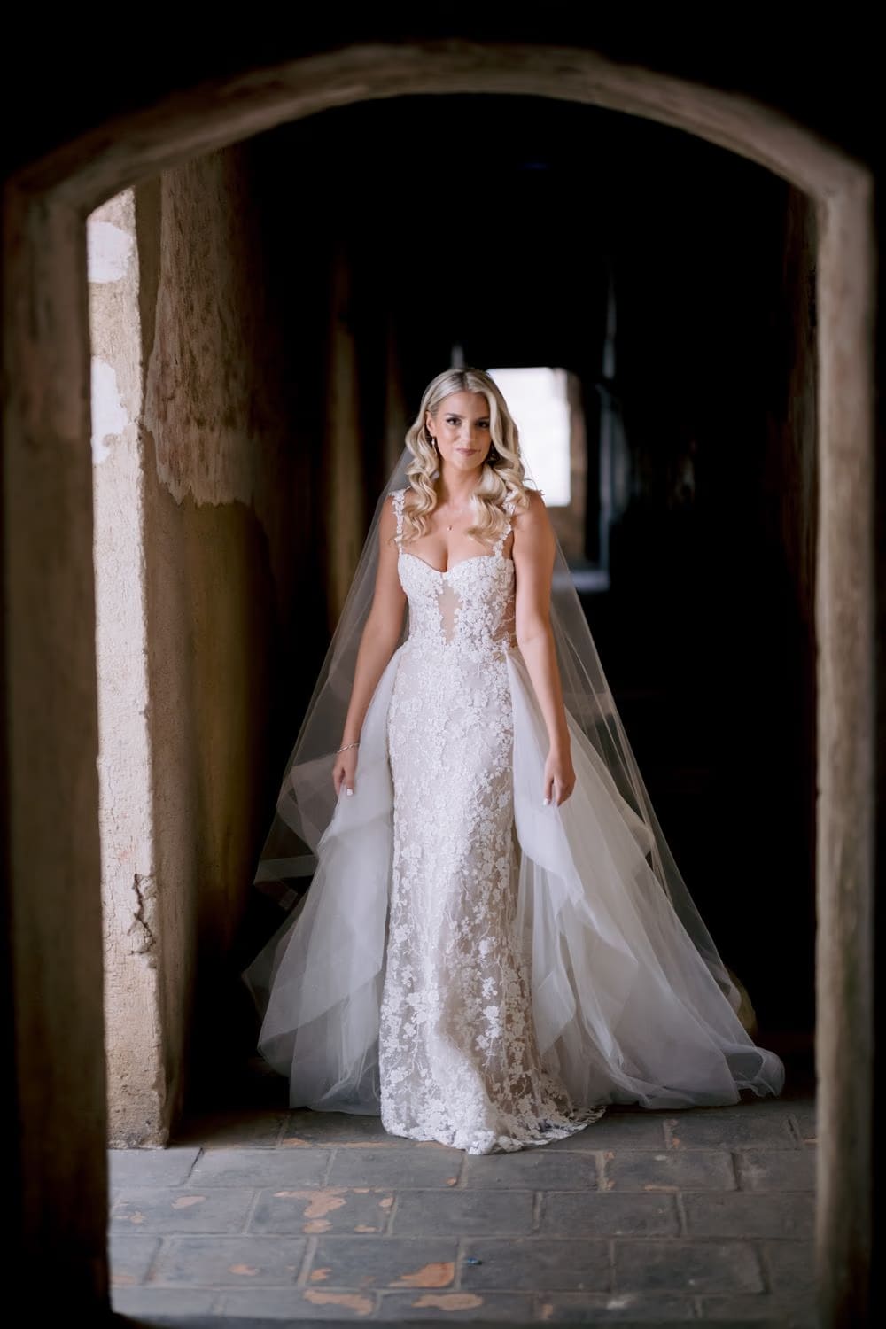 Bride Sydney in lace and tulle gown framed by the cloister arches of Santa Clara — destination bridal portrait.
