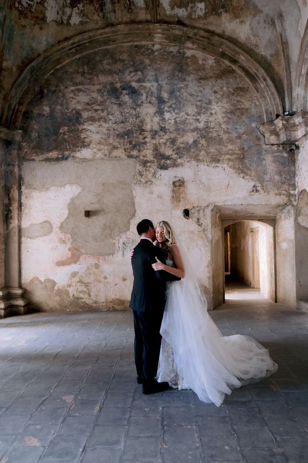 Bride and groom hold each other quietly beneath the vaulted ceiling of Santa Clara Ruins after their first look.
