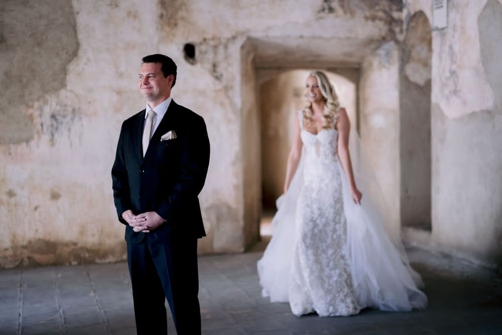 Groom smiles as bride approaches from behind during their first look at Santa Clara Ruins in colonial Antigua.