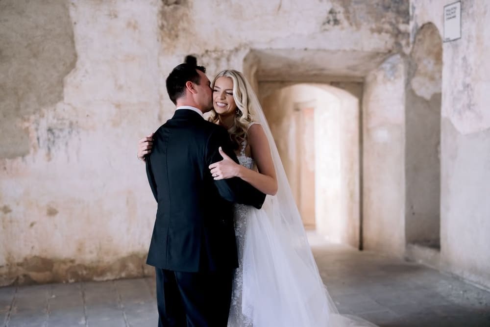 Bride leans into the groom with a smile during their emotional first look at Santa Clara Ruins.