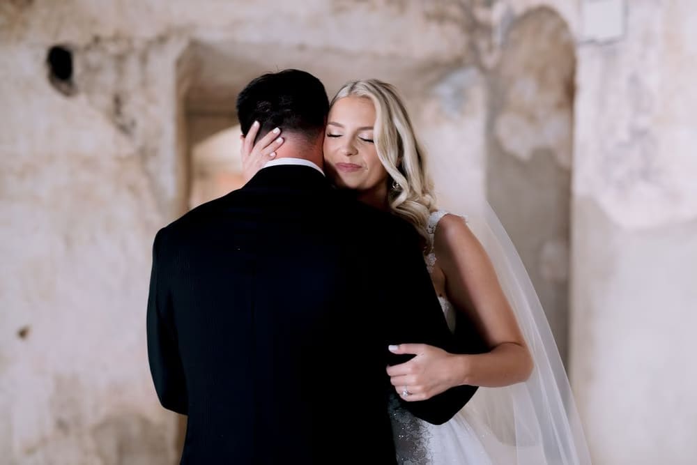 Bride closes her eyes against her groom's shoulder during a quiet first-look moment at Santa Clara Ruins.