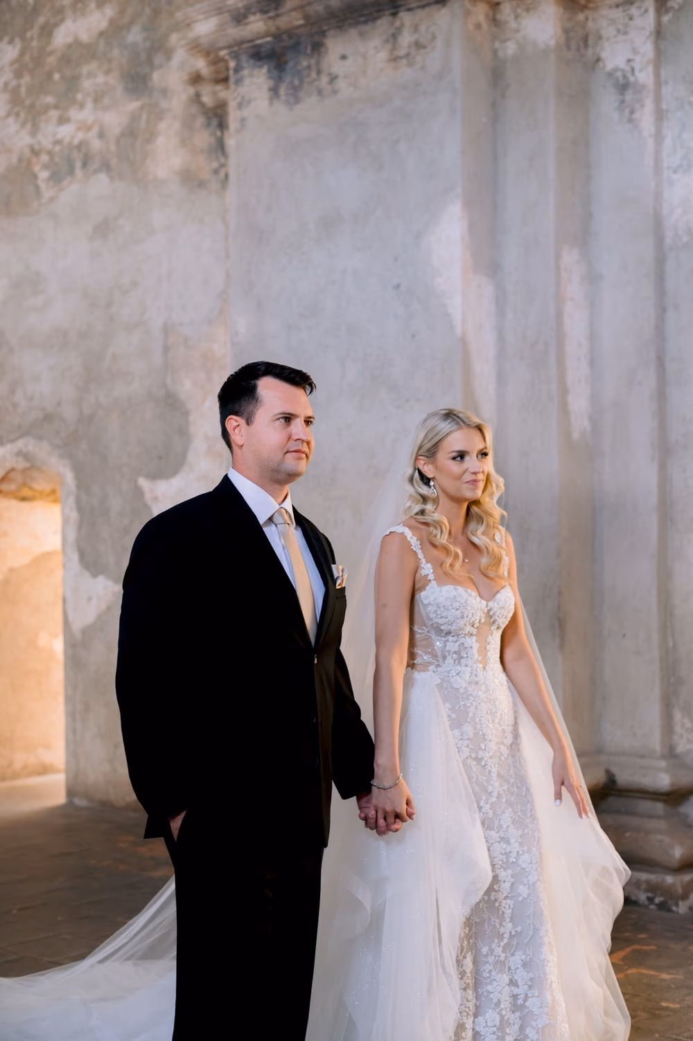 Sydney and Nathan stand side by side beneath the weathered plaster of Santa Clara Ruins for an editorial portrait.