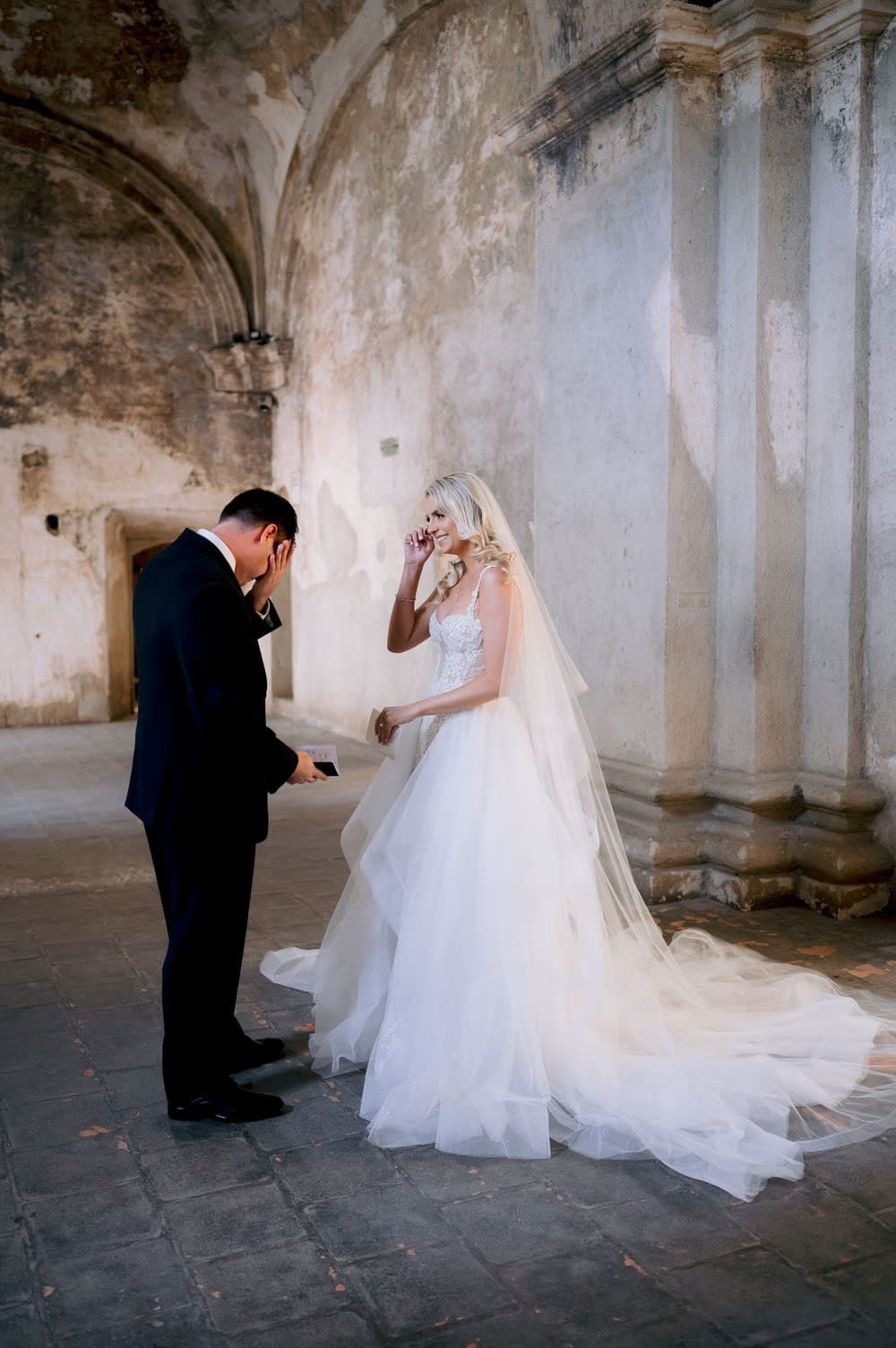 Groom covers his face overwhelmed as the bride wipes a tear before reading their vows at Santa Clara Ruins.