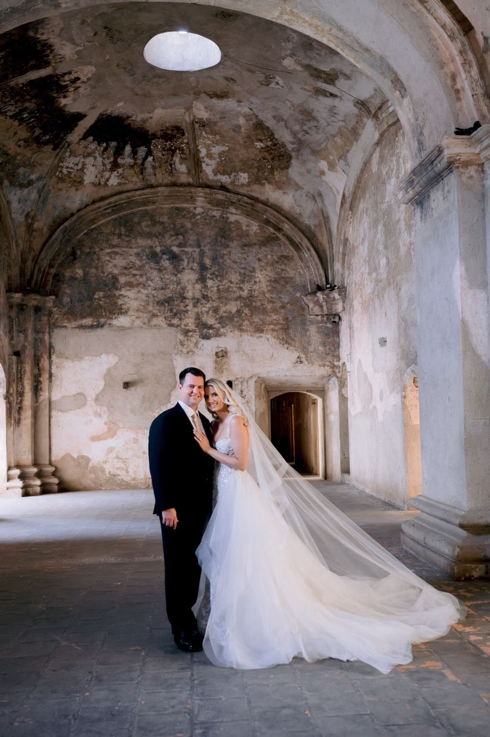 Sydney and Nathan smile beneath the oculus light of Santa Clara's vault — editorial couple portrait in Antigua Guatemala.