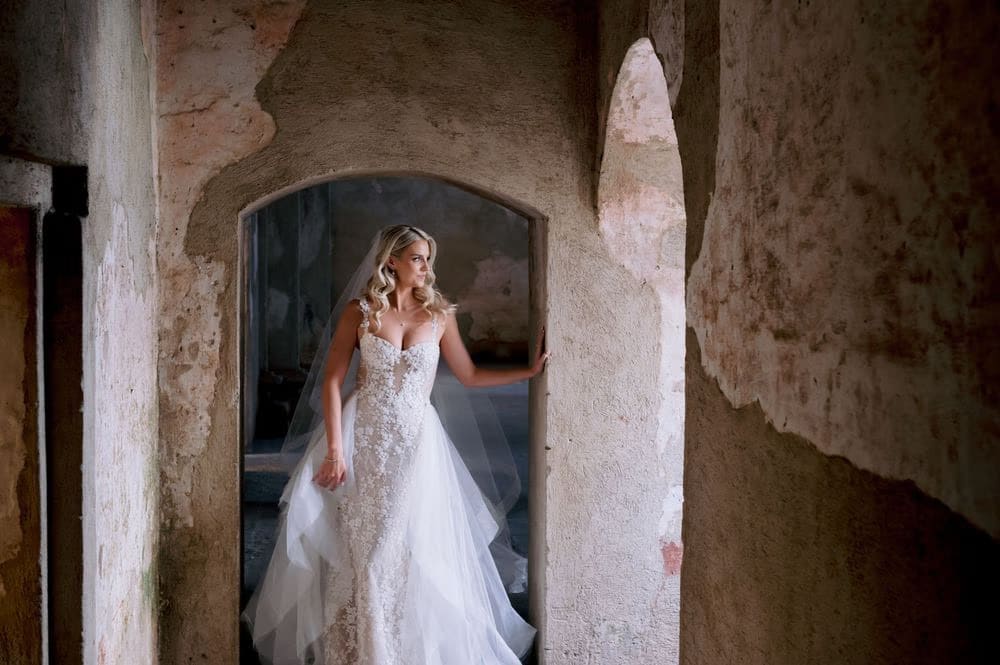 Bride leans into an arched doorway at Santa Clara, veil draping along her shoulder.
