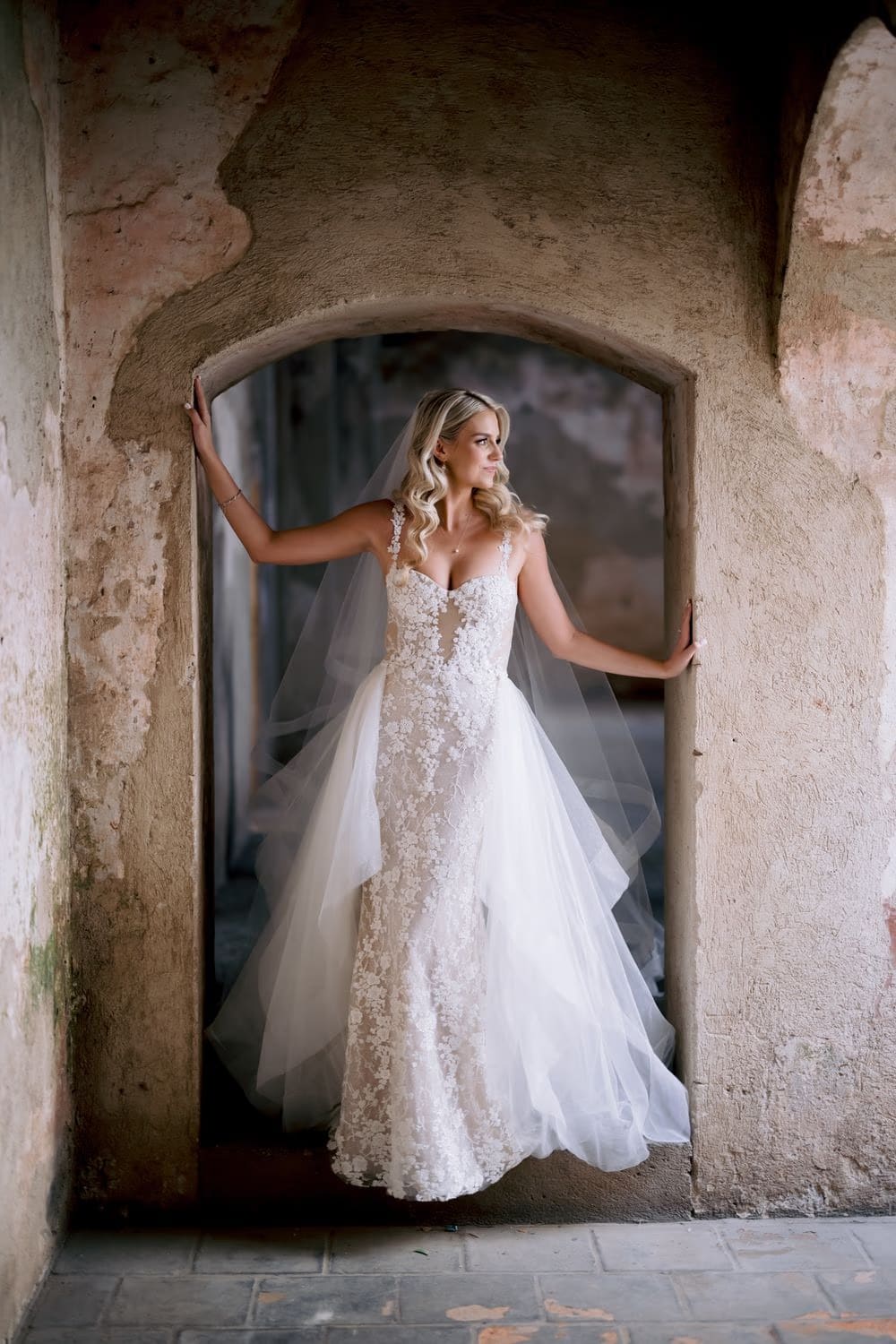 Bride glances off-camera framed by an arched doorway at Santa Clara — editorial bridal portrait in La Antigua.