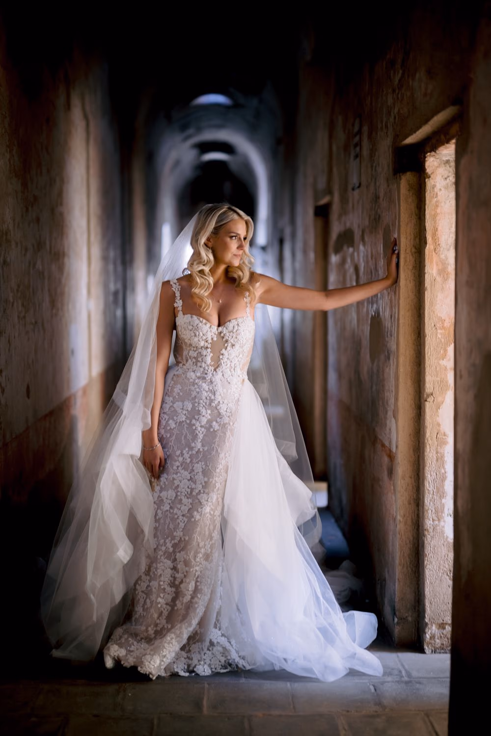 Bride pauses in a long stone corridor at Santa Clara Ruins — destination bridal portrait in colonial Antigua.