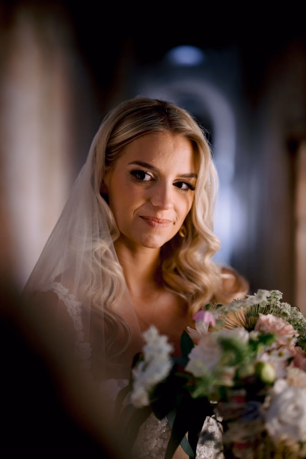 Close-up portrait of bride Sydney smiling softly, framed between corridor walls in Antigua Guatemala.