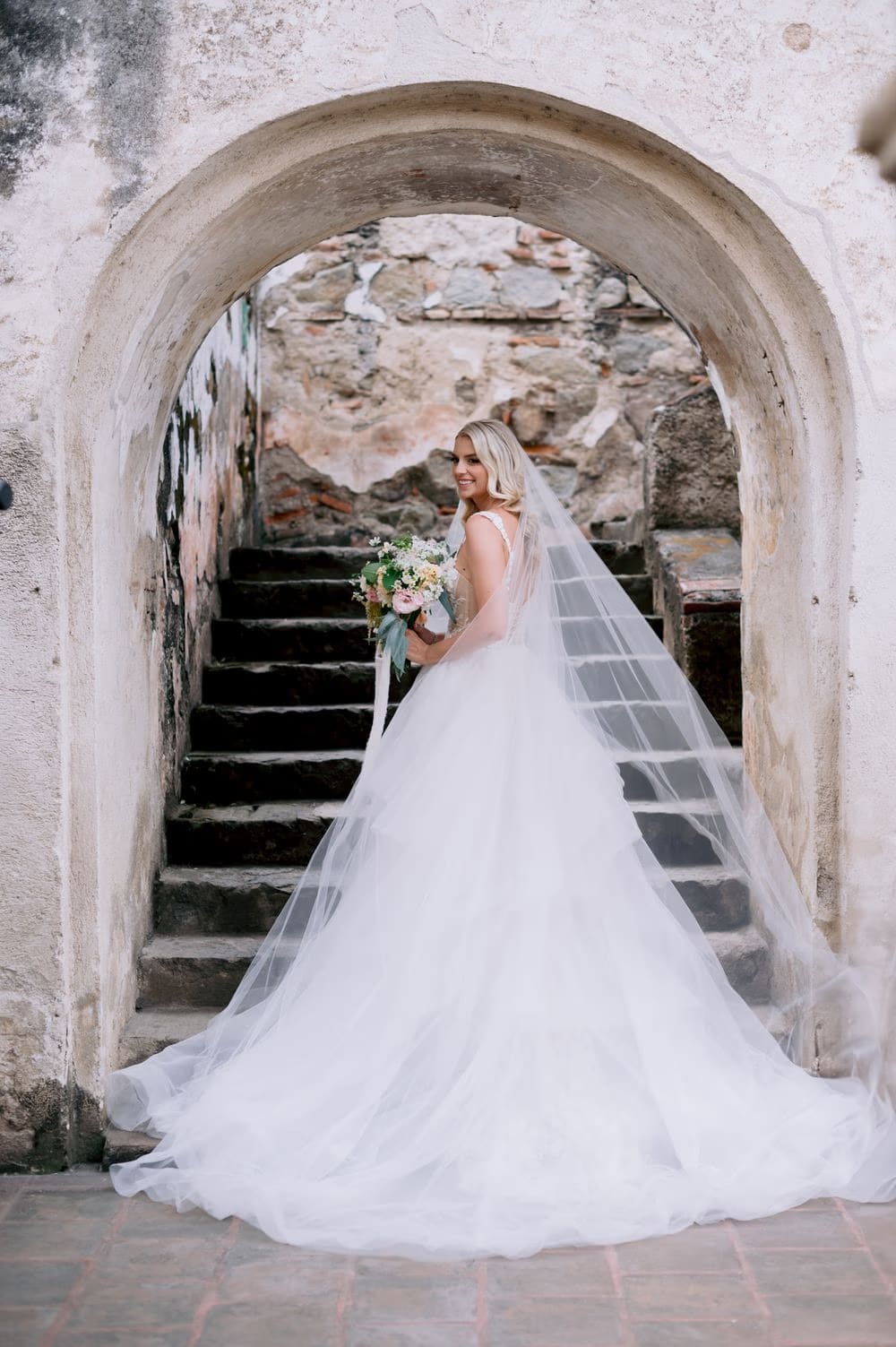 Bride poses on the cinematic stone staircase of La Recolección Ruins, veil cascading down the steps.