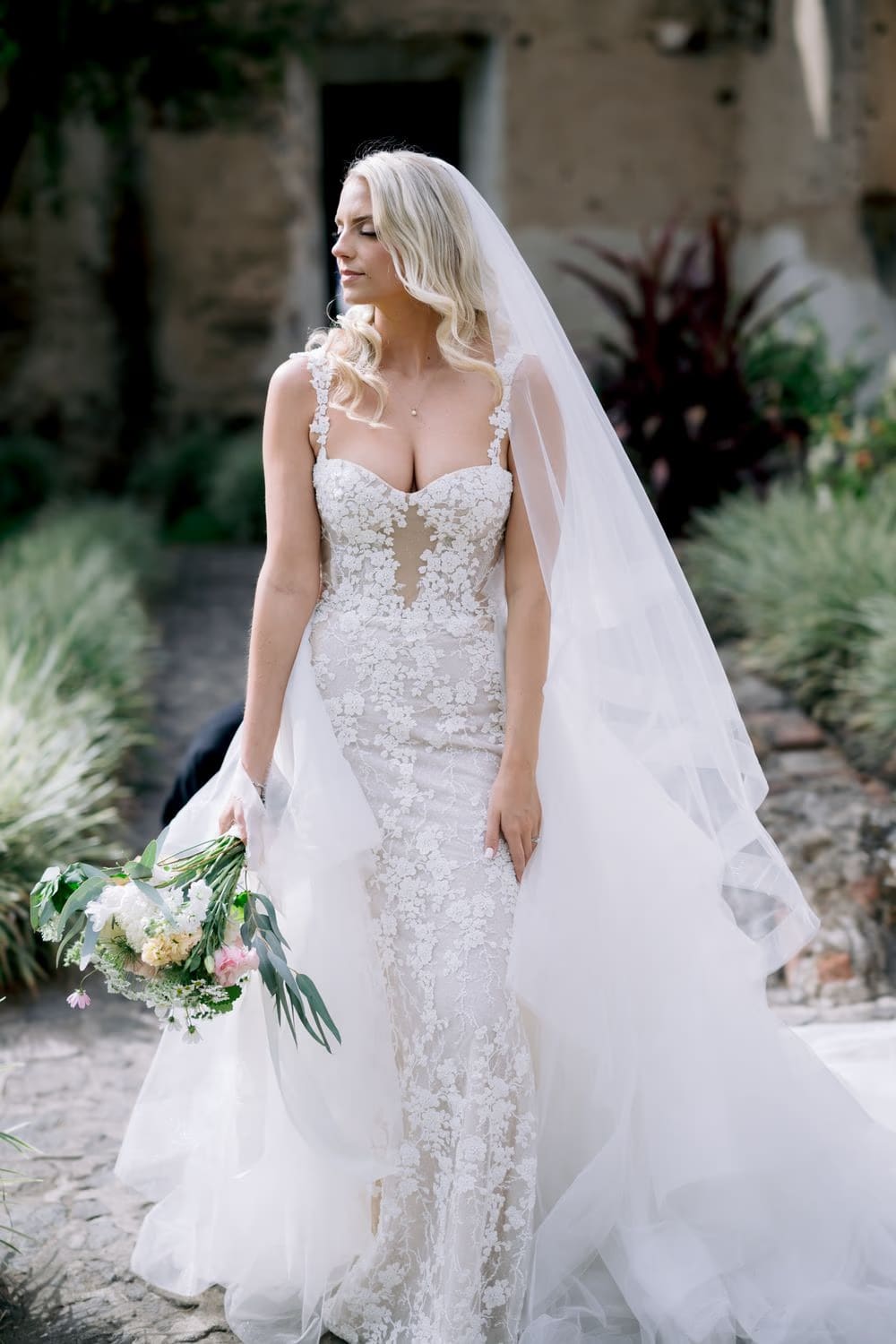 Bride pauses with her bouquet in a garden corner — soft and pensive bridal portrait in Antigua Guatemala.