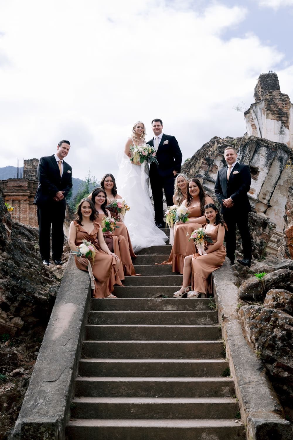 Bride and groom stand on the upper ruin walls of La Recolección for a sweeping portrait above colonial Antigua.