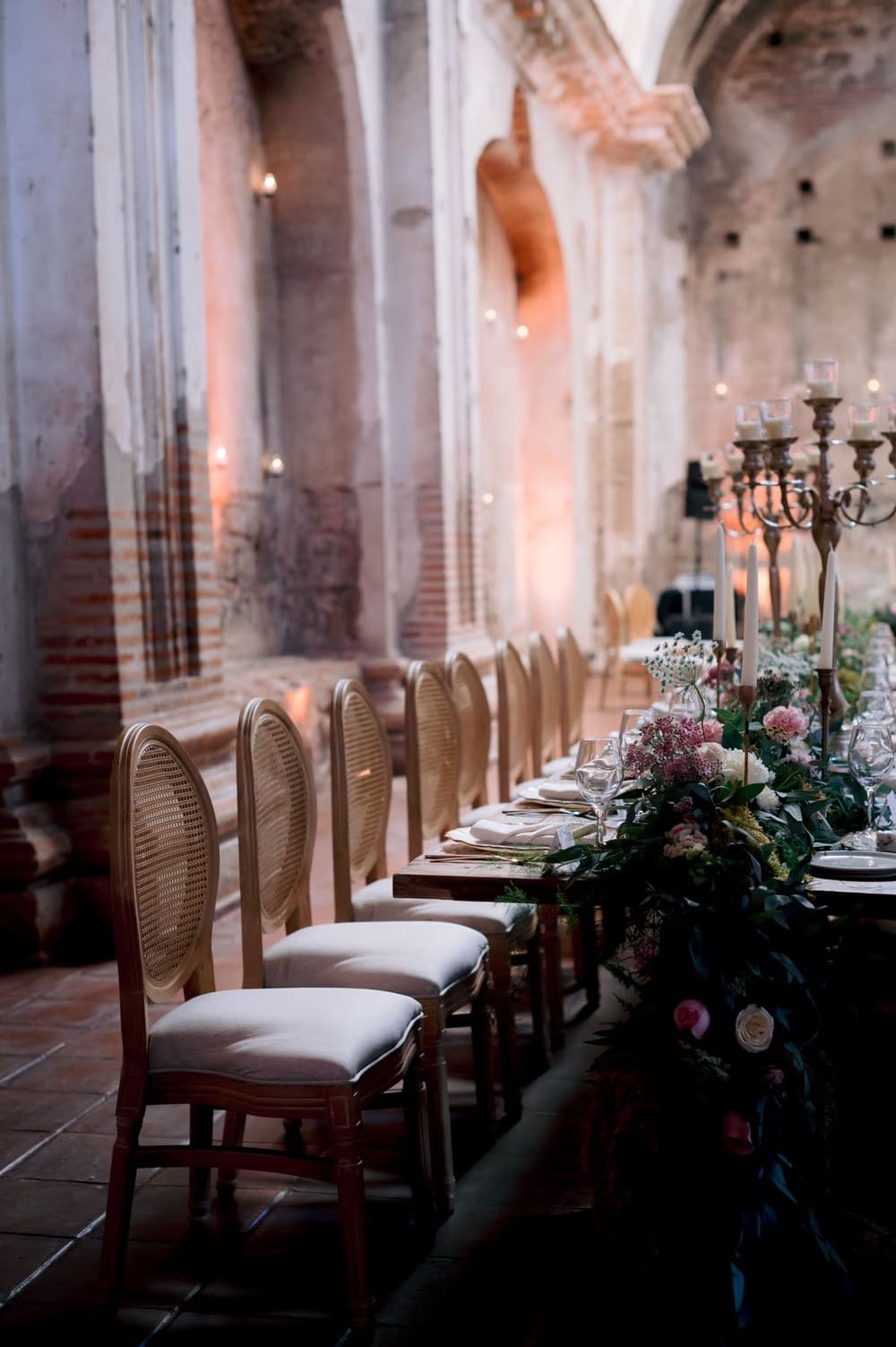 Cane-back chairs line the long wooden reception table along the candle-lit columns of San José el Viejo.