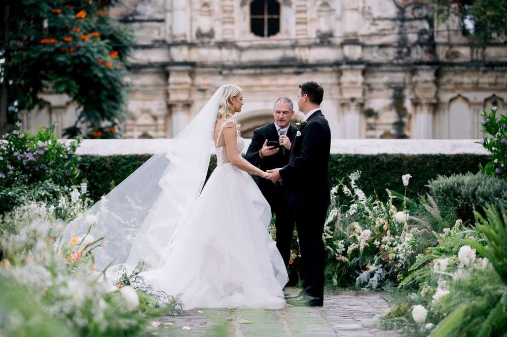 Bride and groom exchange vows beside the officiant during the garden ceremony at San José el Viejo Ruins.