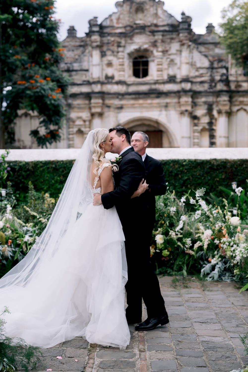 Bride and groom share their first kiss as a married couple in front of the San José el Viejo facade in Antigua Guatemala.