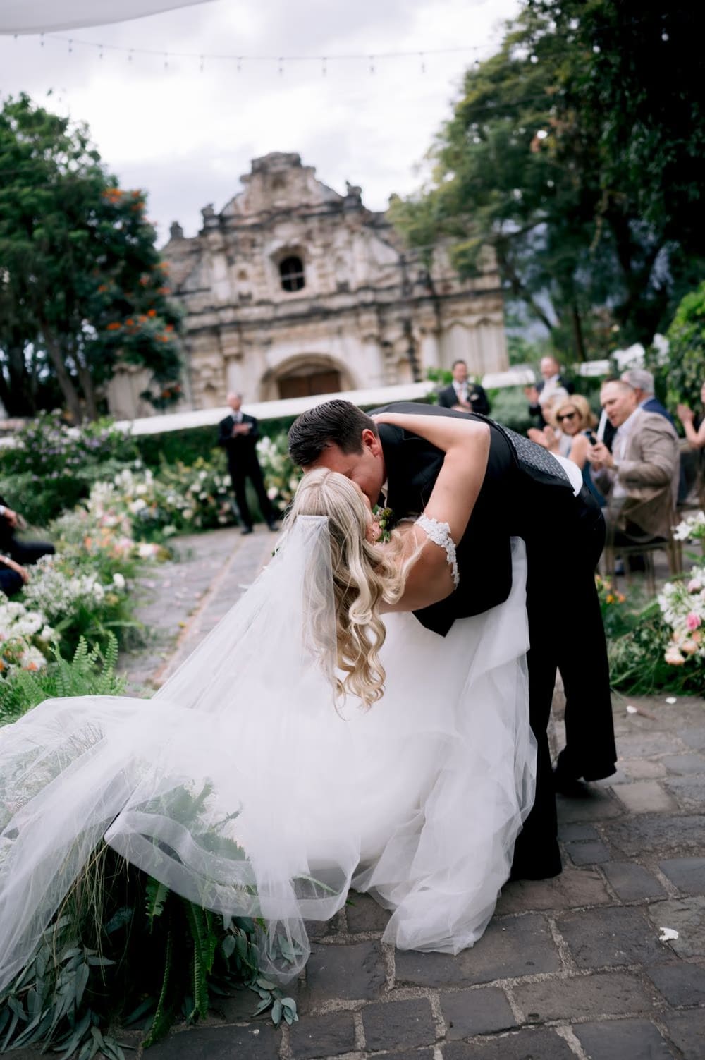 Groom dips the bride for a kiss at the end of the aisle as guests cheer behind them — San José el Viejo wedding moment.