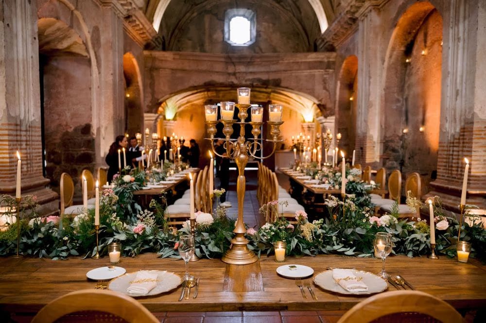 Detail of a centerpiece candelabra surrounded by garlands and tapers along the reception table at San José el Viejo.