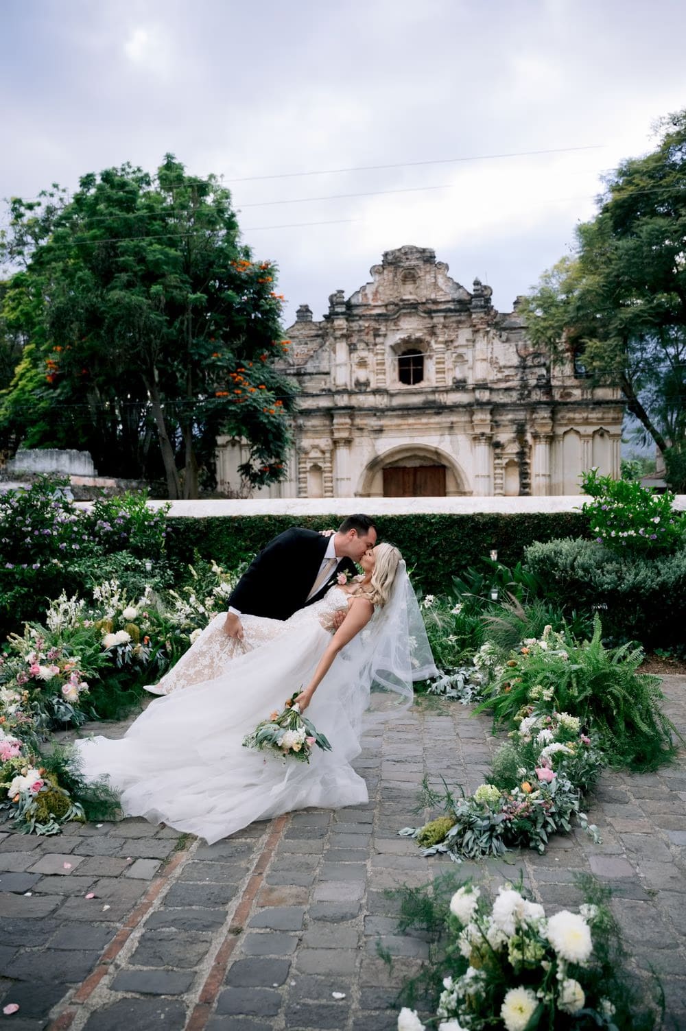 Groom dips the bride for a kiss in front of the San José el Viejo Ruins in colonial Antigua.